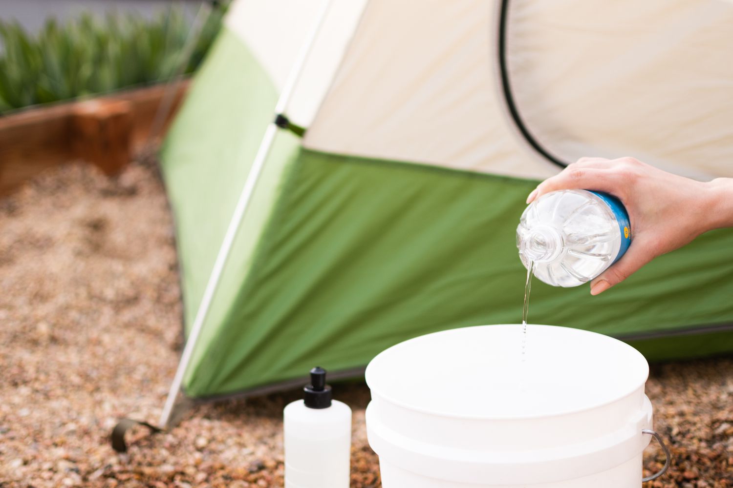 Distilled white vinegar and dishwashing liquid mixed with water in white bucket for tent cleaning solution