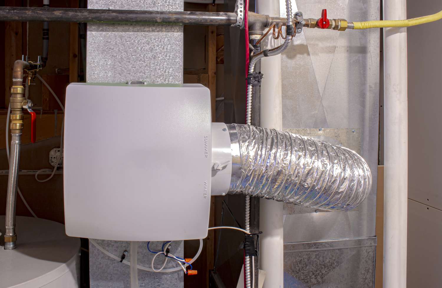Um umidificador doméstico conectado ao duto de retorno com uma conexão de desvio para o duto de ar quente de fornecimento.