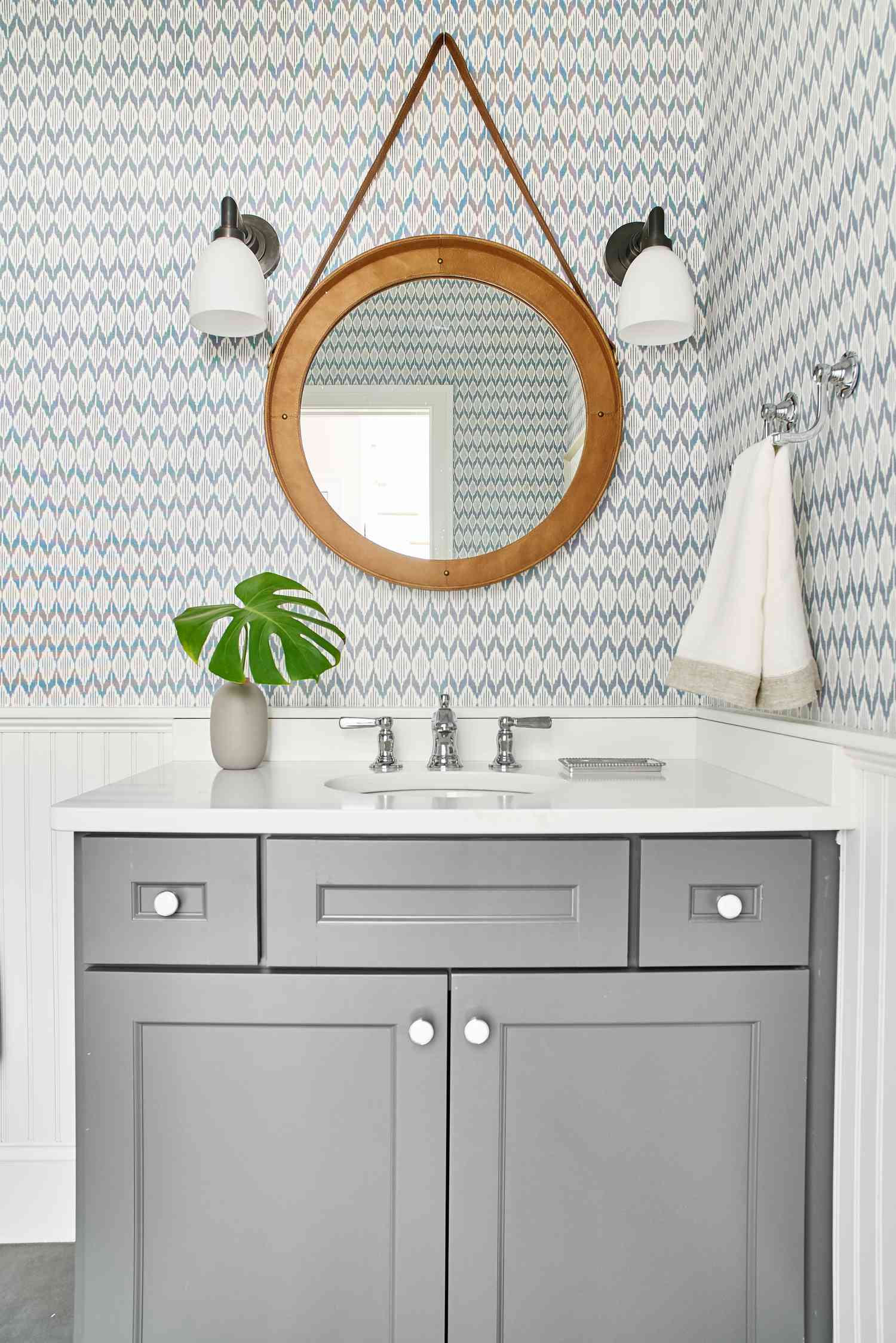 Tocador gris con espejo redondo de madera y papel pintado azul y blanco