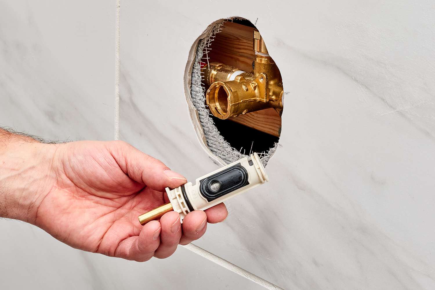 Moen pressure-balanced shower valve held in front of exposed shower valve stem