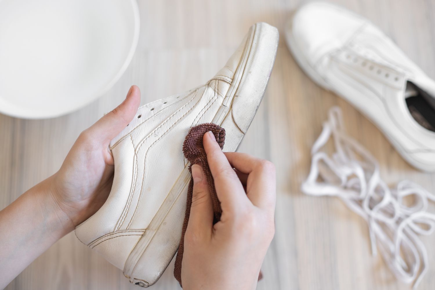 Feuchtes Mikrofasertuch wischt losen Schmutz von weißen Leder-Van-Schuhen