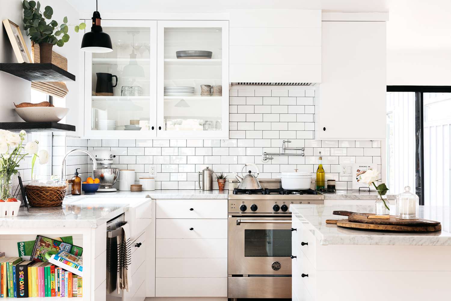 Cozinha branca moderna decorada com parede de tijolos atrás do forno de aço inoxidável