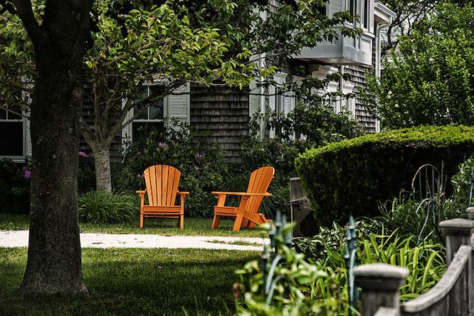 Sillas Adirondack de color naranja vivo en un jardín sombreado