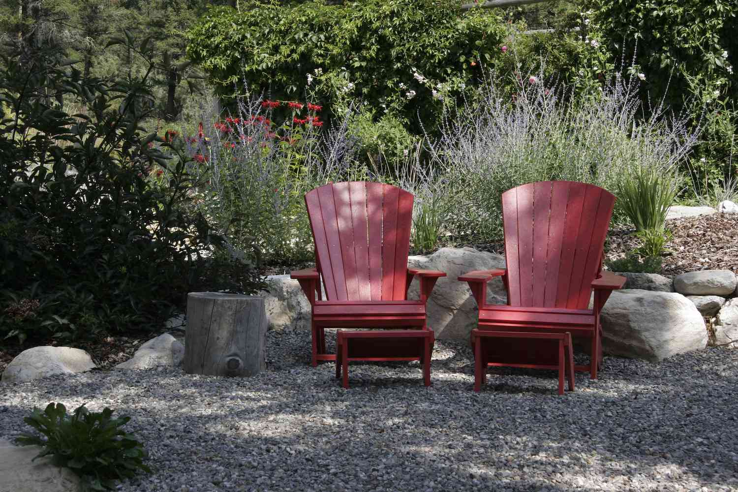 Paar rote Adirondack-Stühle mit russischem Salbei und roter Bienenmelisse