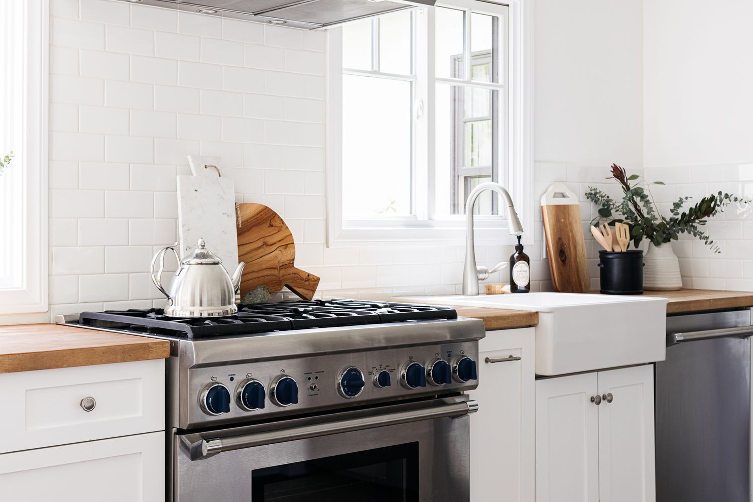 Cocina moderna con pared de azulejos blancos y encimera de bloques de carnicero