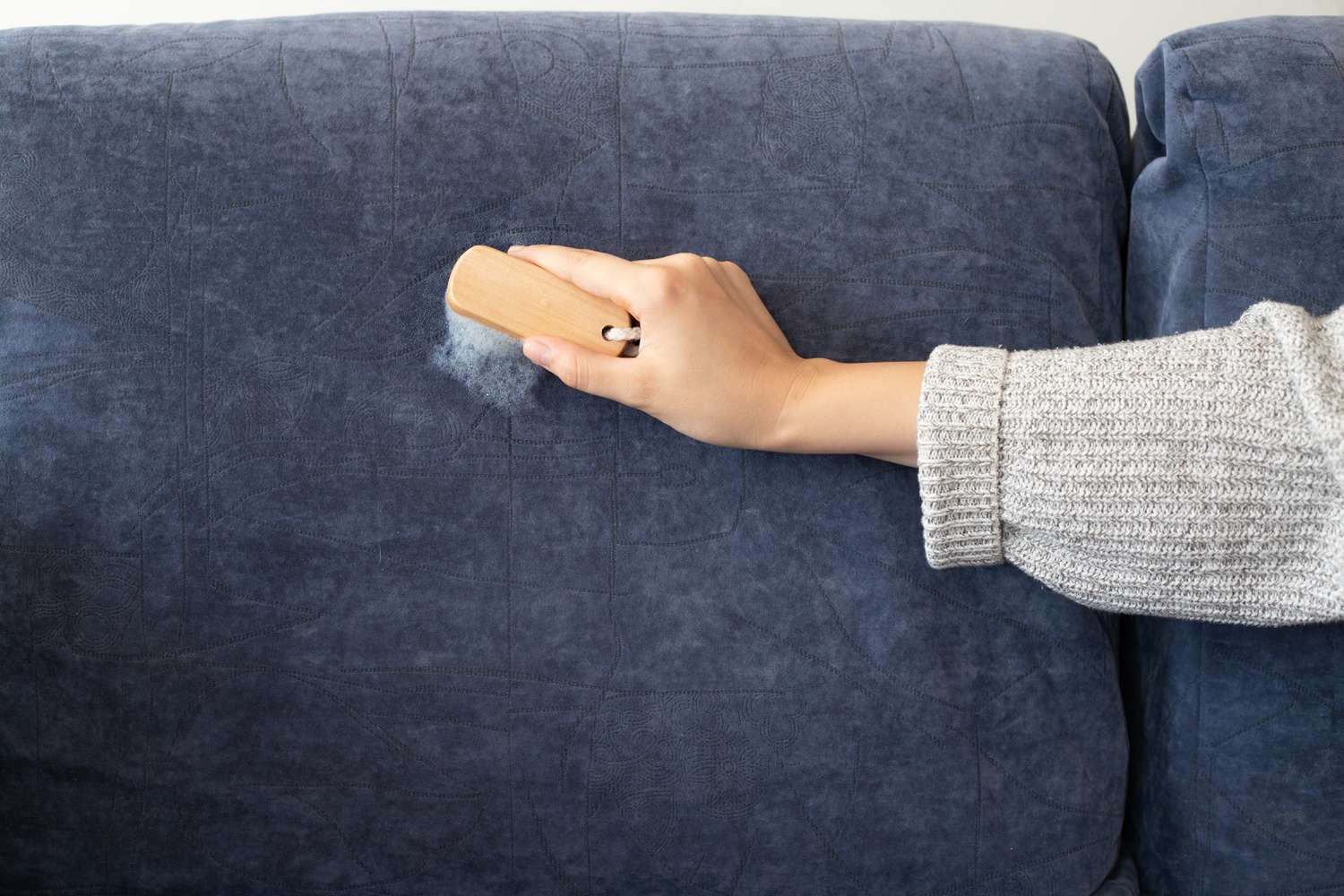 Escova de esfregar esfregando solução de limpeza no sofá de microfibra azul