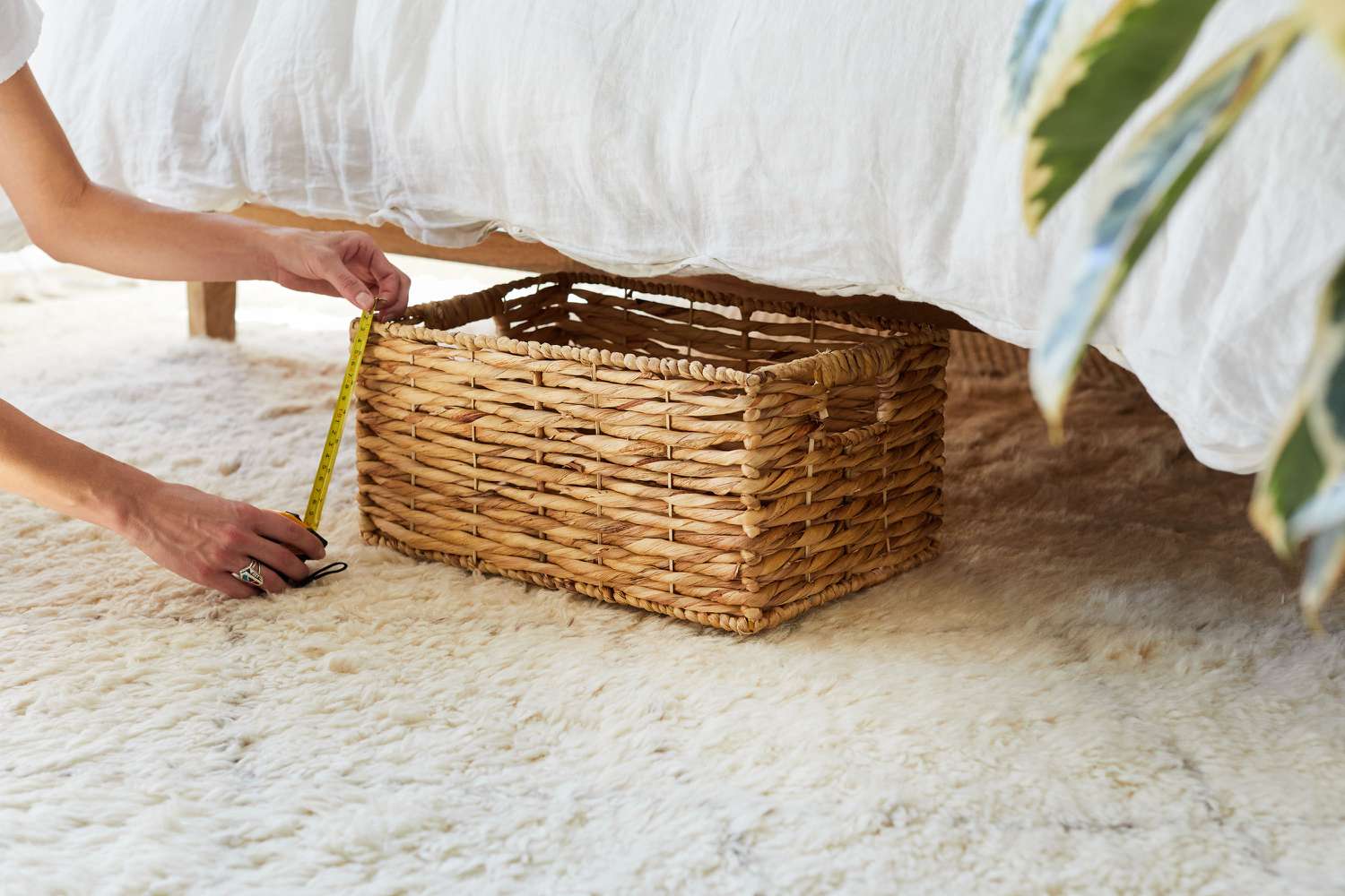 Wicker basket being measured with measuring tape under the bed