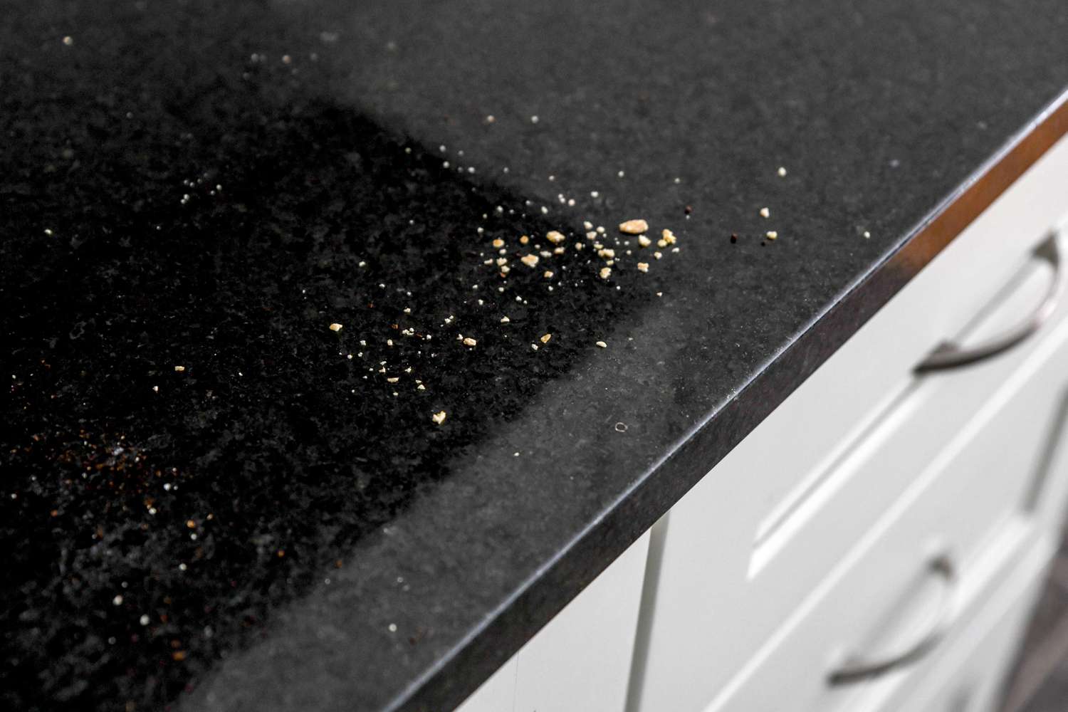 Food crumbs on black kitchen counter