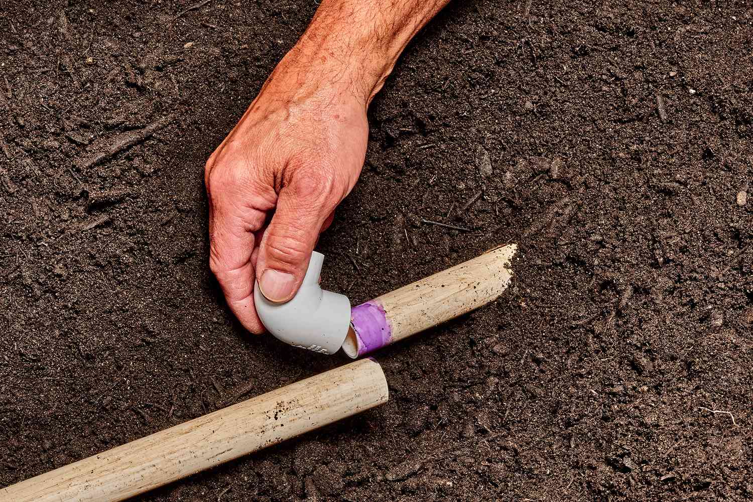 Codos de 90 grados de PVC colocados y pegados en el extremo de la tubería de agua cortada