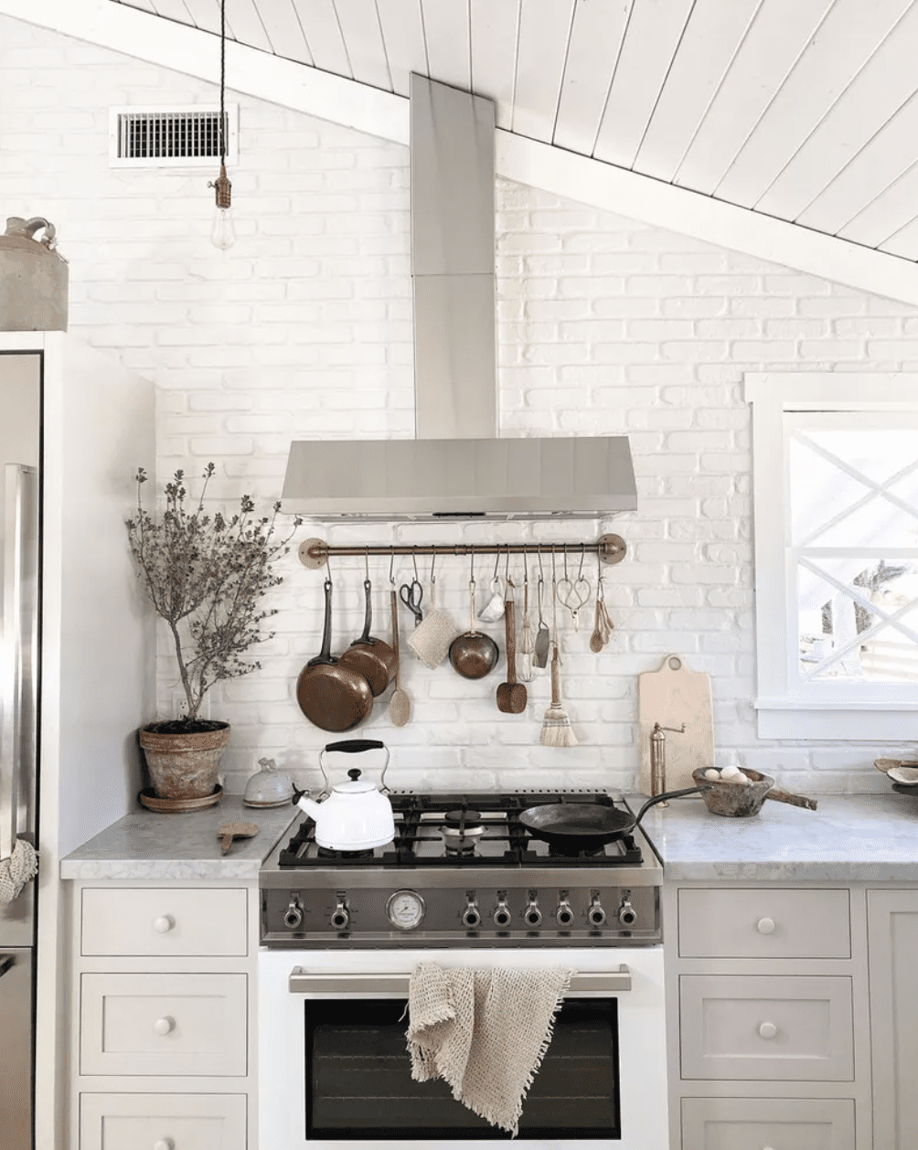 Eine kleine weiße Küche mit einer schrägen Decke und einer Dunstabzugshaube, die entsprechend geformt wurde