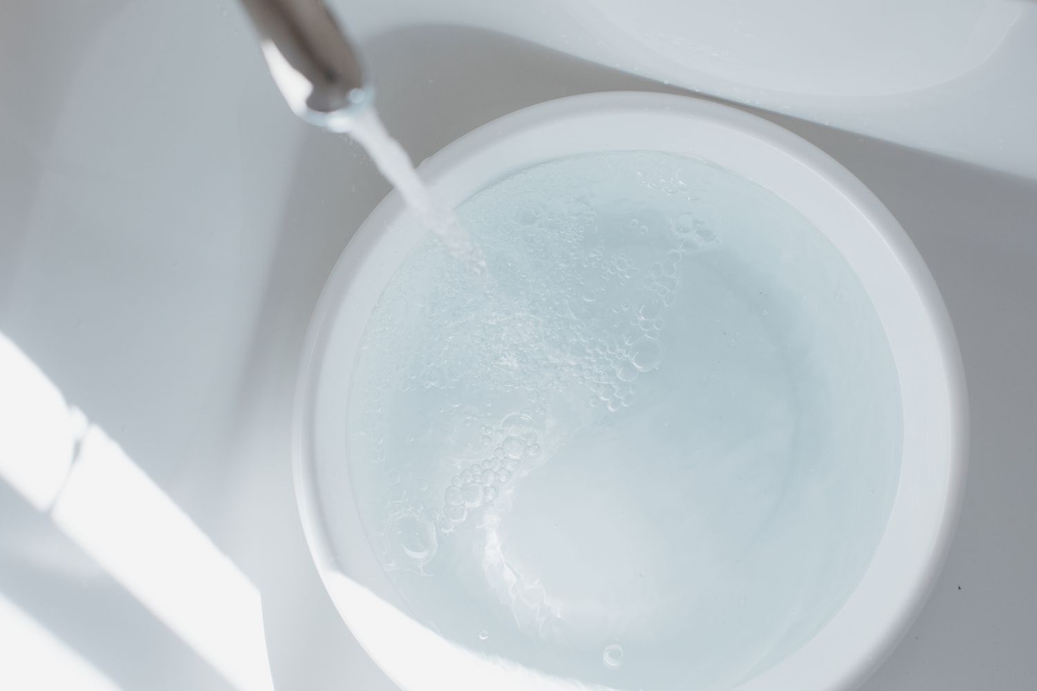 Faucet running with bucket underneath collecting water