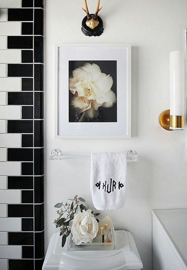Baño en blanco y negro con flores blancas y detalles dorados