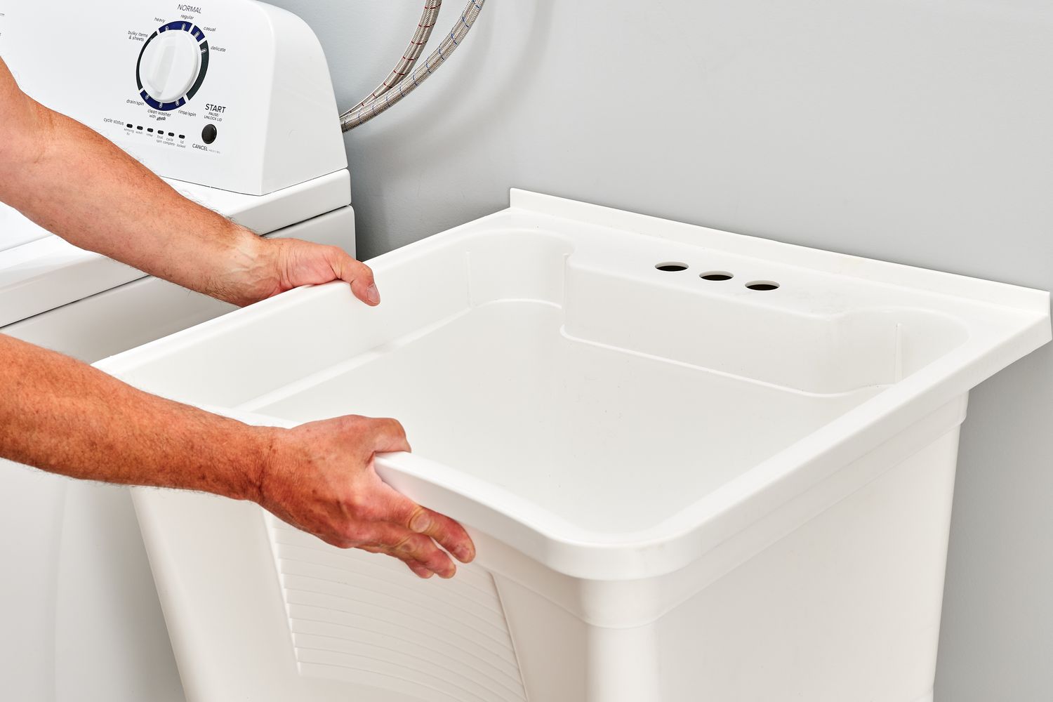 Laundry room sink placed against wall and washing machine to assess size