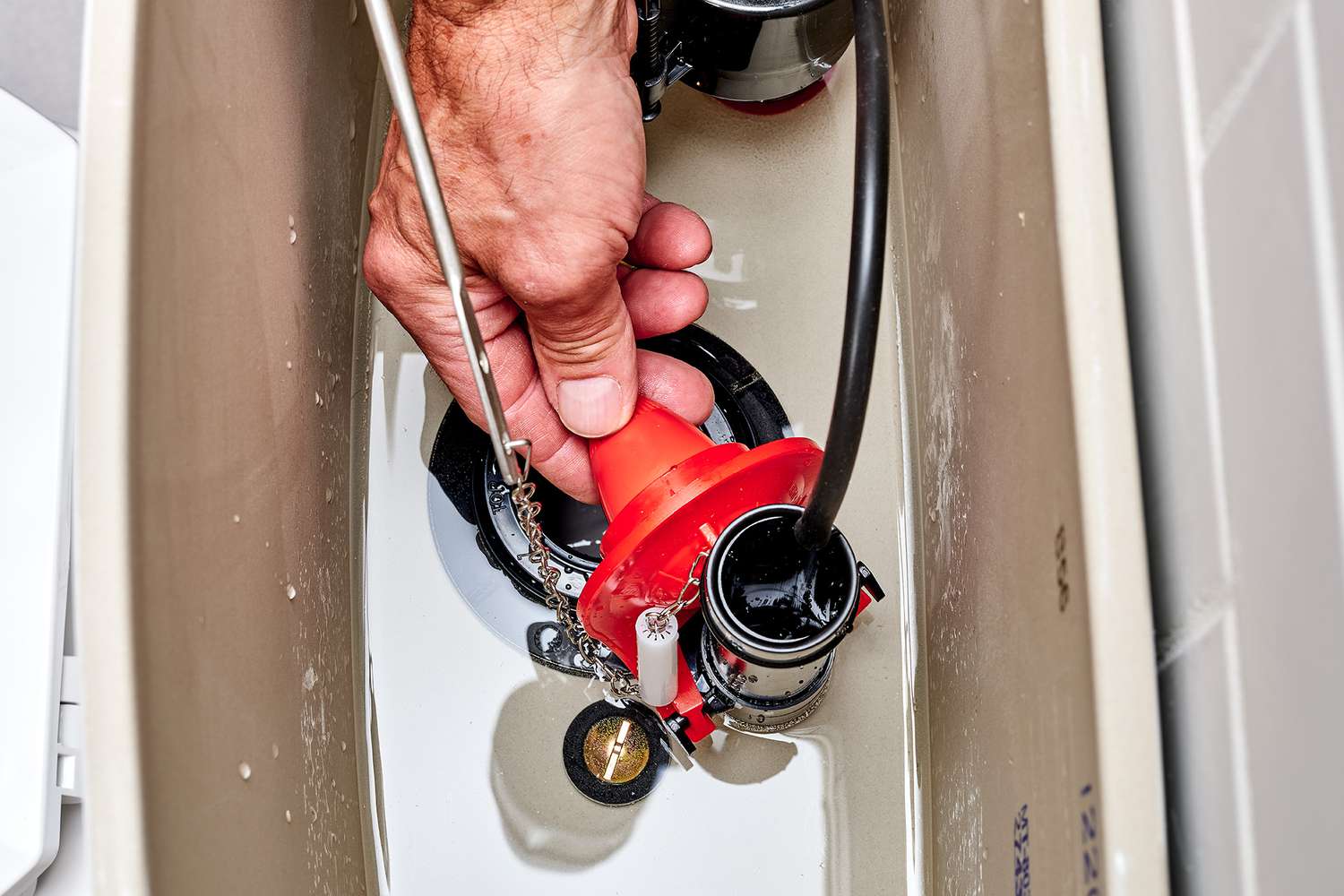 Trampilla ajustable naranja instalada para controlar el flujo de agua al tirar de la cadena