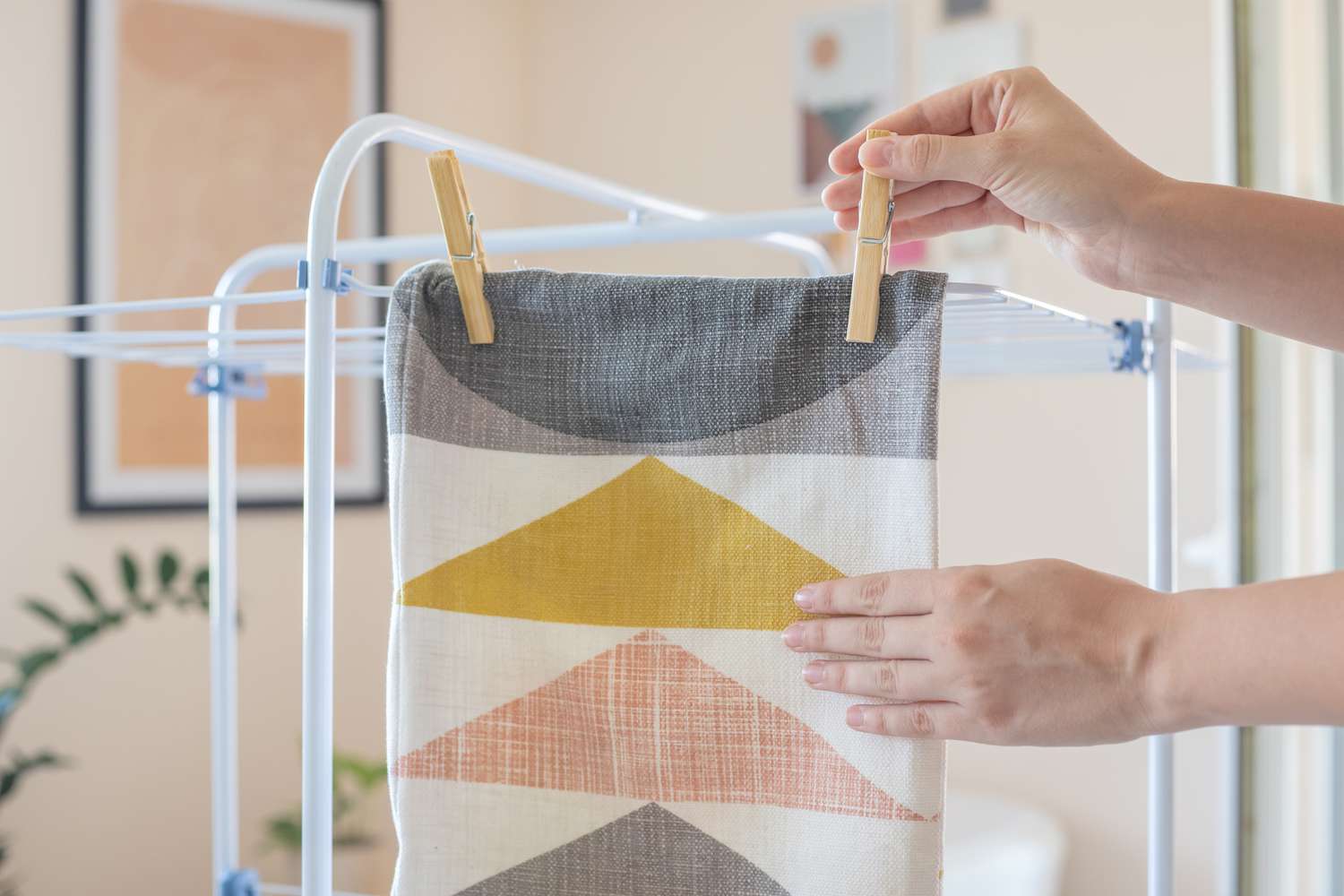 Patterned throw pillow cover clipped to drying rack with clothes pins