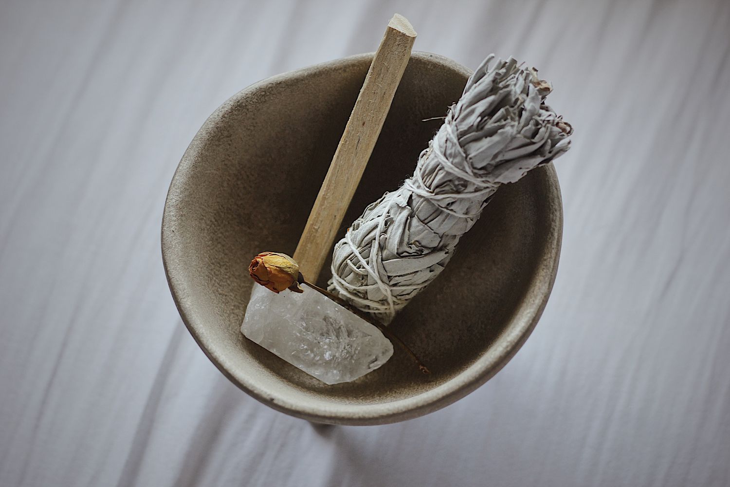 cuenco de cerámica con un cristal, palo santo y salvia