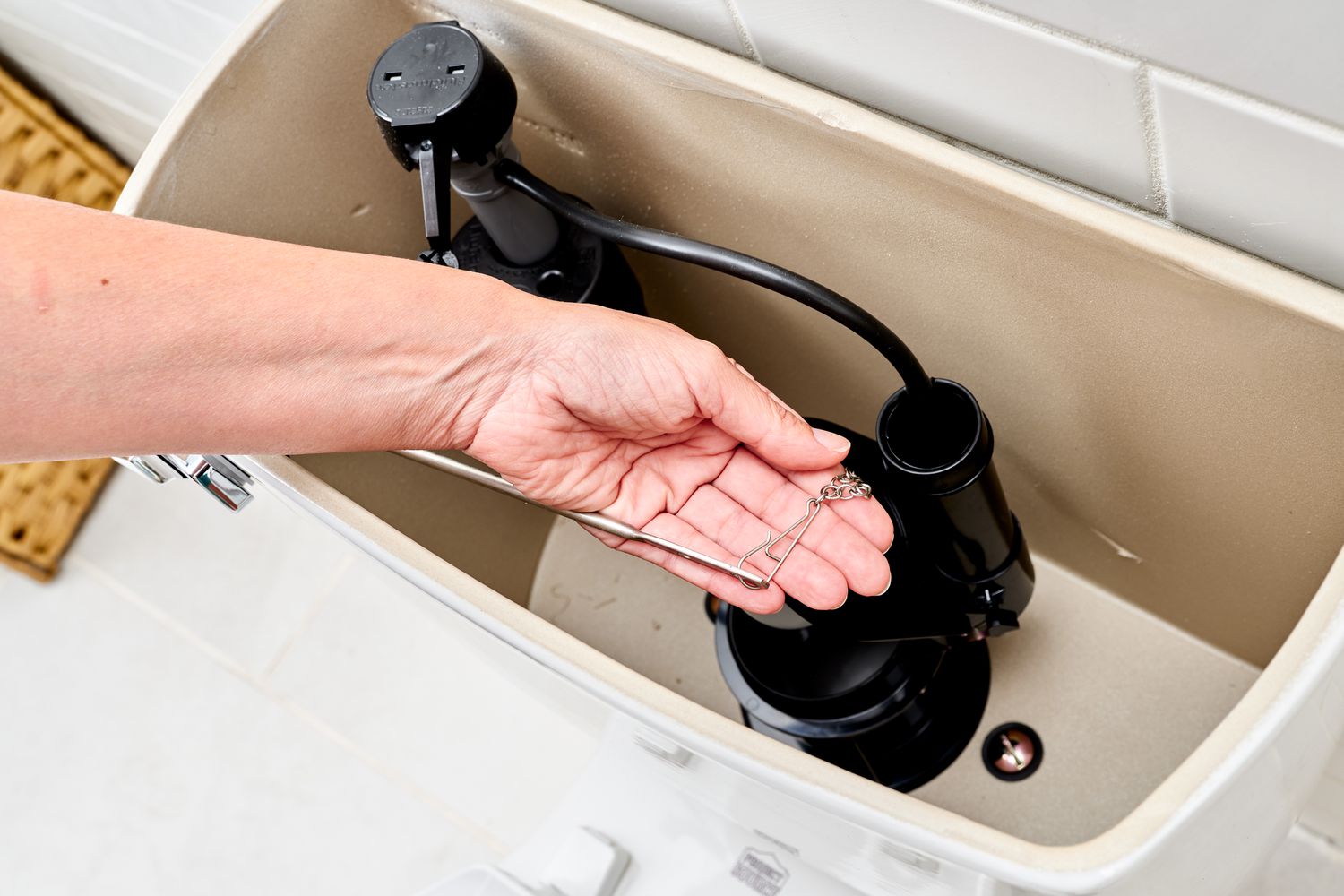 Flapper chain held in hand inside toilet tank