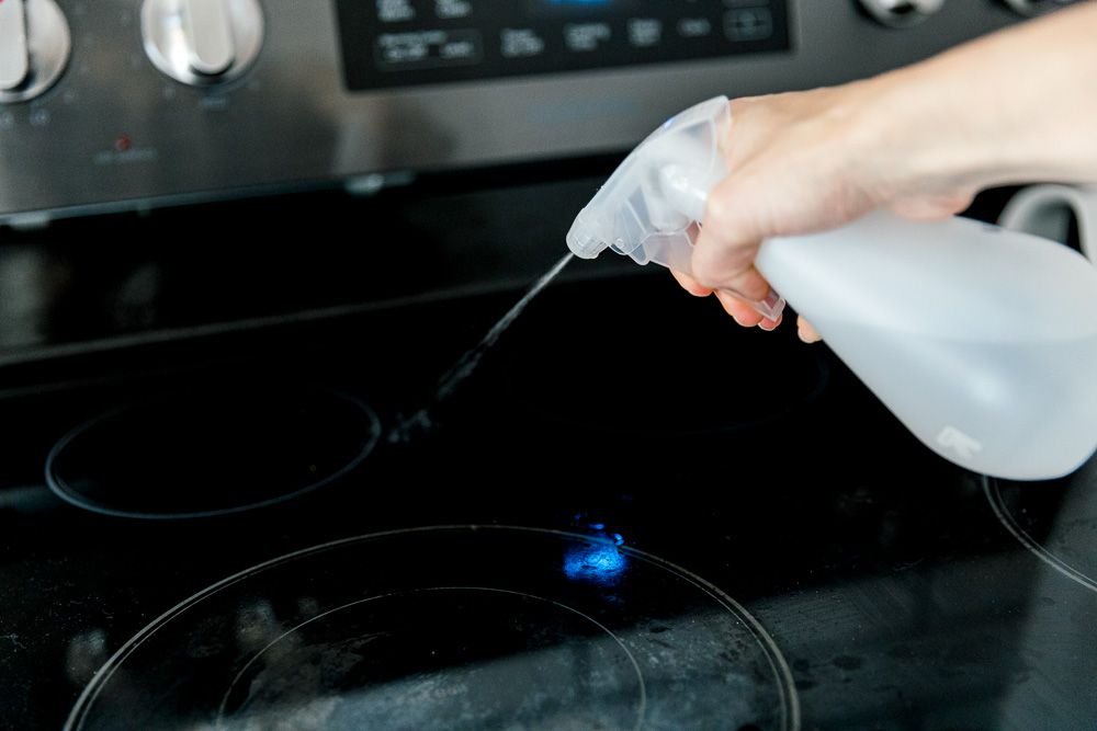 spraying cleaning solution on the cooktop