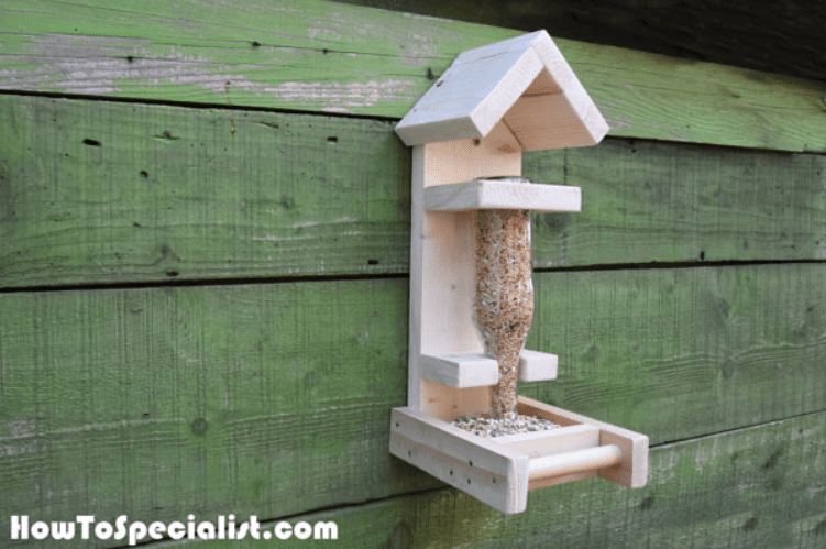 Wooden bird feeder with feed in a bottle