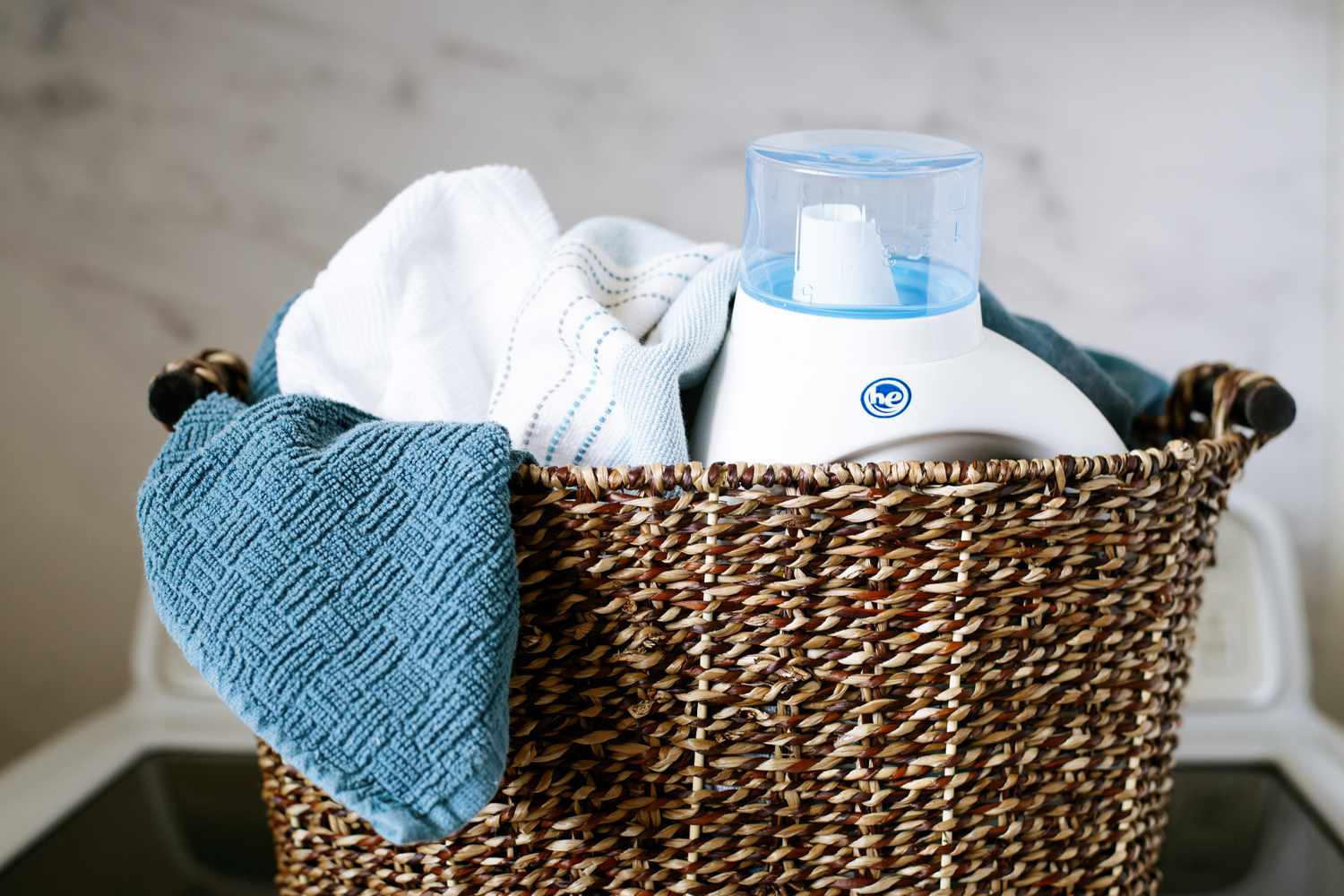Wäschekorb gefüllt mit Handtüchern und Waschmittel