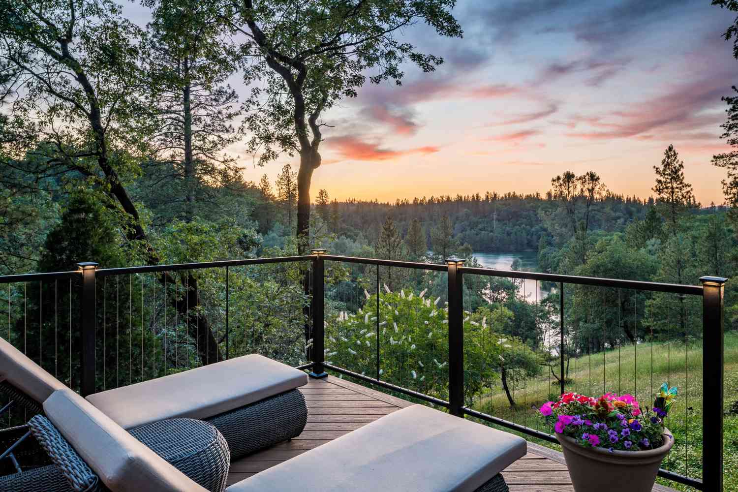 Eine Terrasse mit zwei Liegestühlen mit Blick auf ein Feld und einen Teich