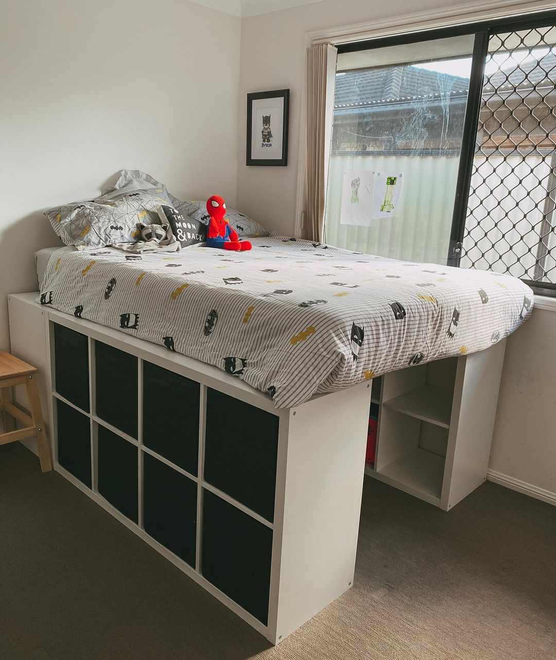 La cama de un niño convertida en altillo mediante cubos de almacenaje.