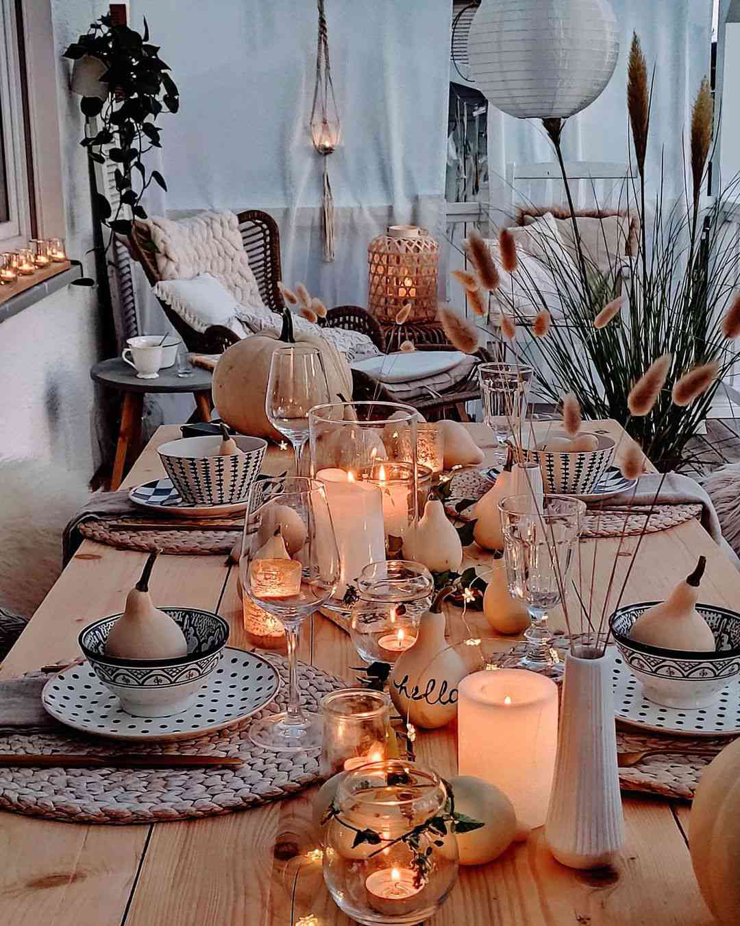 Gedeckter Tisch mit Kerzen, Kürbissen und Lichterketten