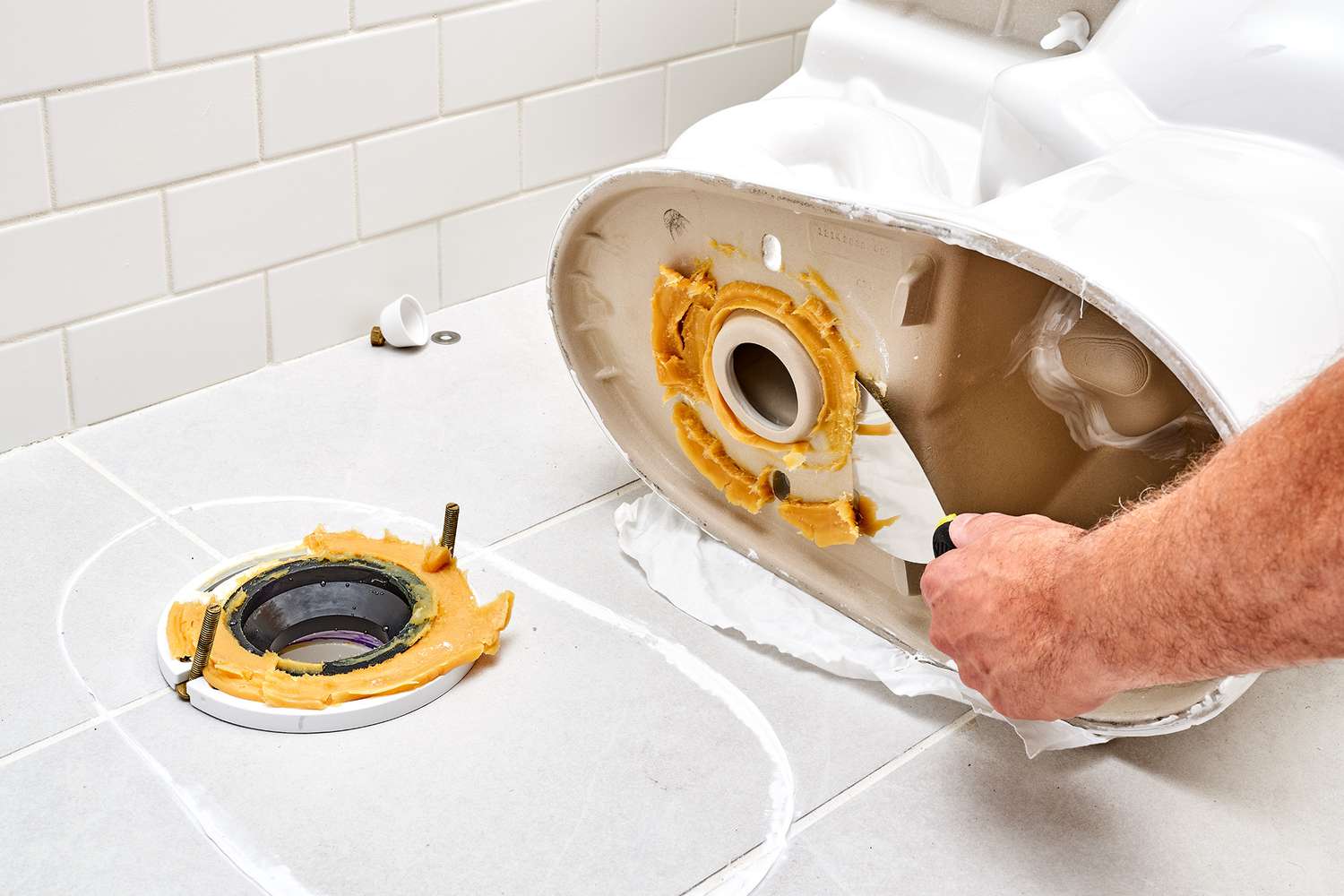 Parte inferior do vaso sanitário limpa com uma espátula para raspar a cera velha para limpeza