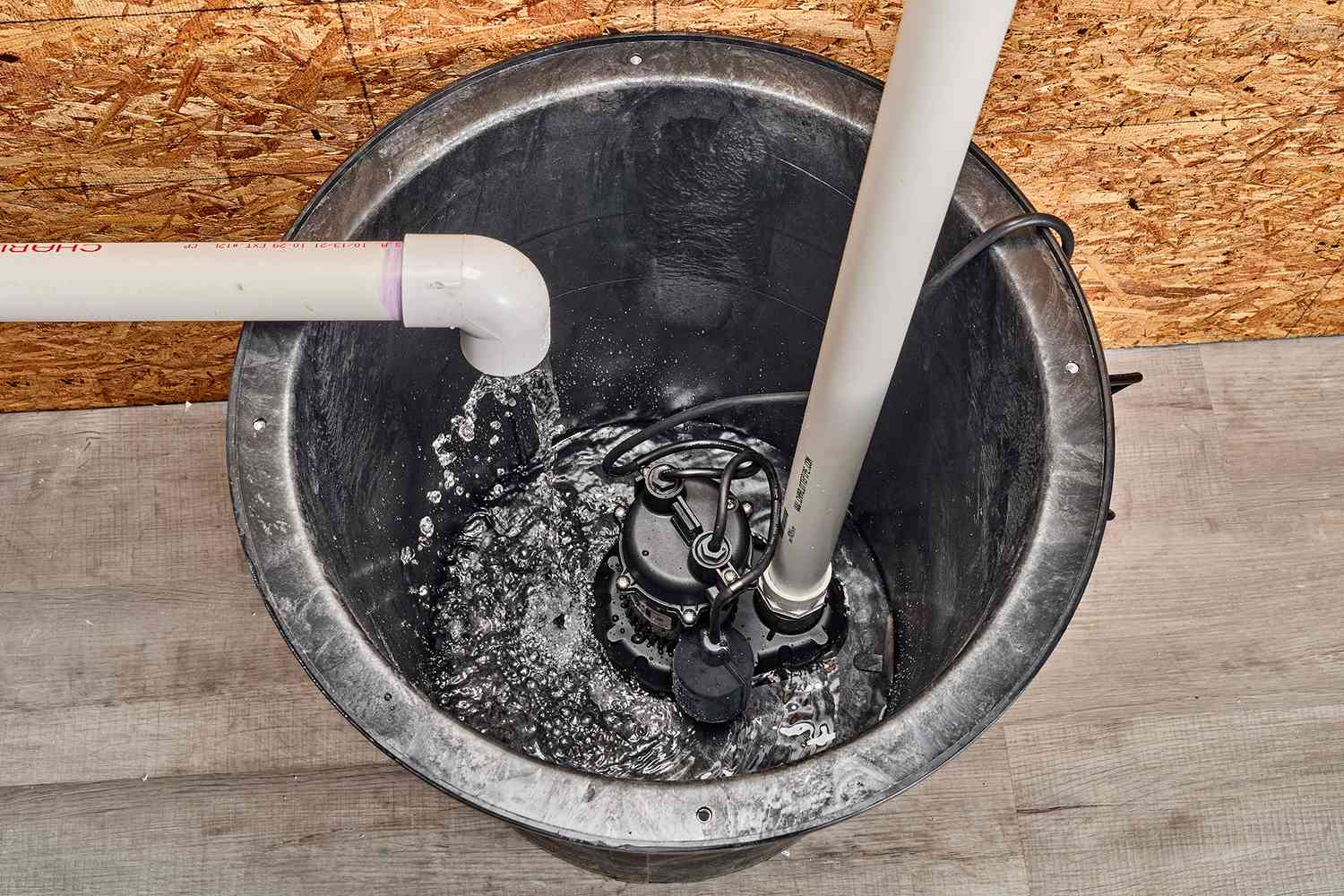 Freigelegte Sumpfpumpe mit aus dem PVC-Rohr einströmendem Wasser
