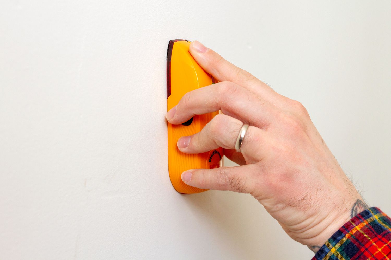 Orange stud finder placed flat against wall