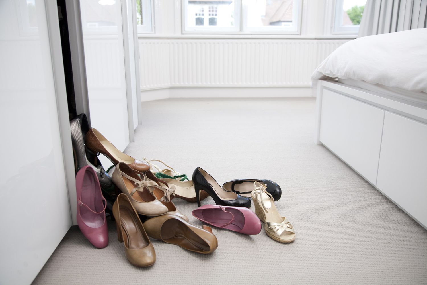 Mehrere verschiedene Paar Schuhe auf dem Schlafzimmerboden.