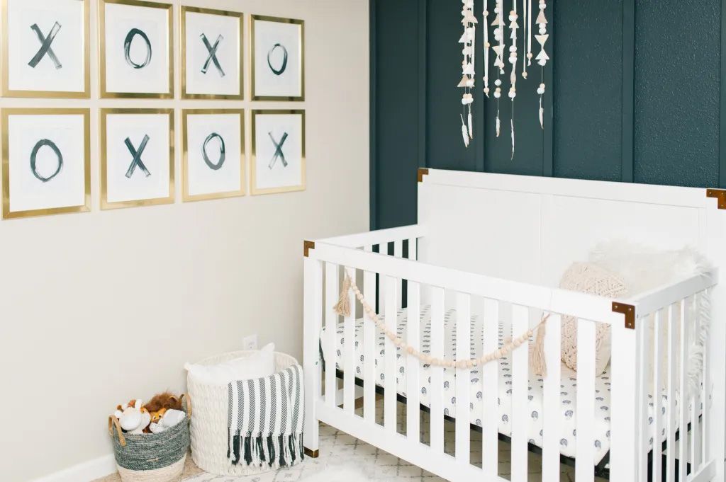 Um quarto de bebê com um berço, arte na parede e um móbile