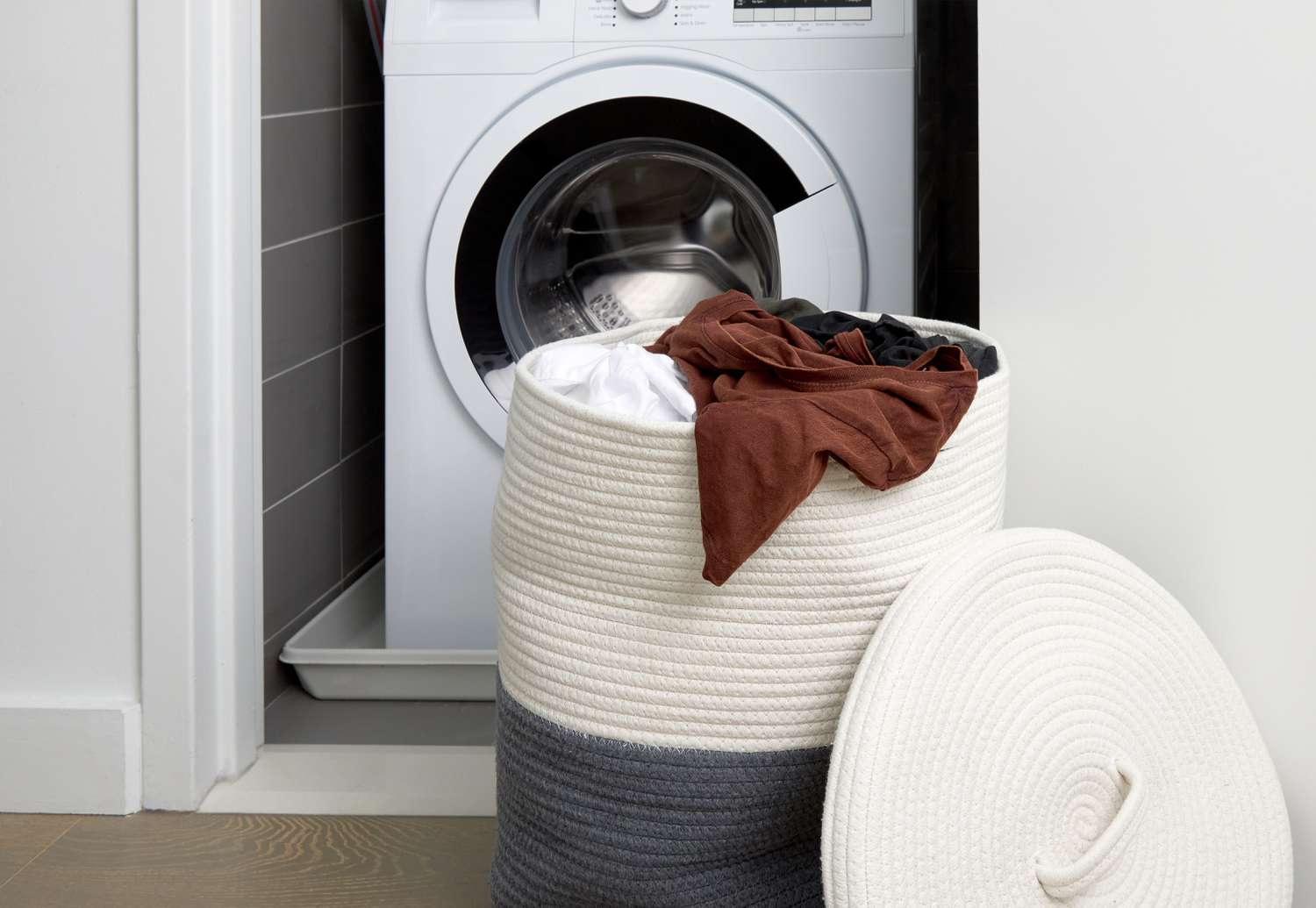 cesto de roupa suja em frente a uma lavadora