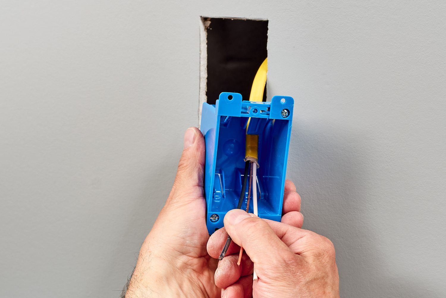 In die Wandöffnung eingesetzter Altbau-Elektrokasten mit abisoliertem Kabel