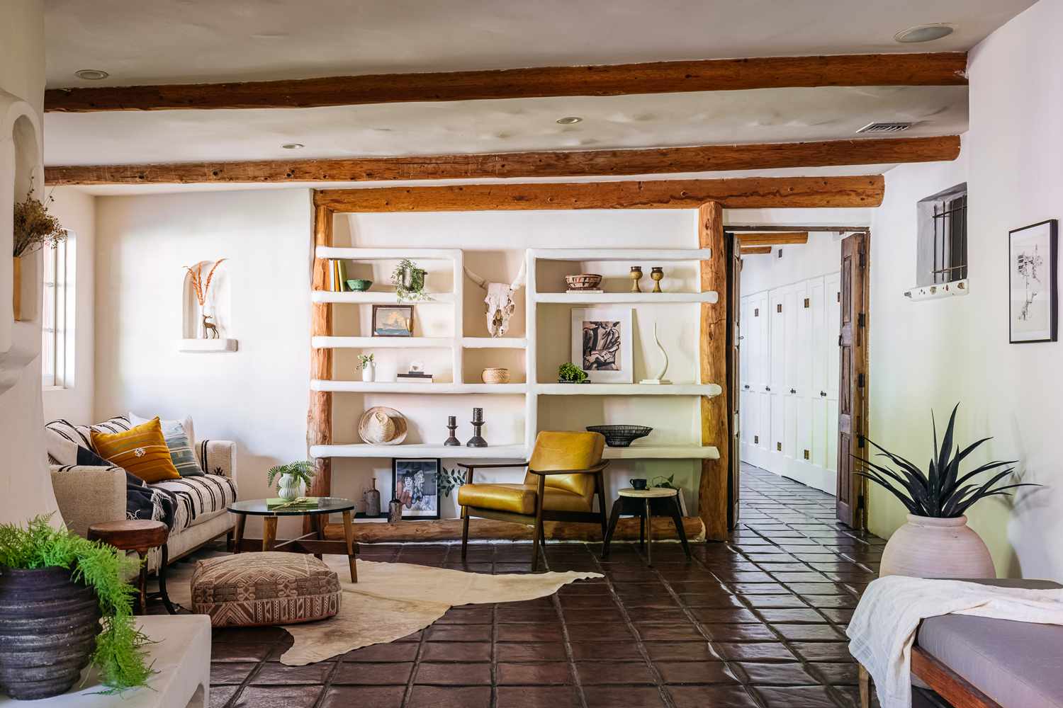 Sala de estar em estilo mediterrâneo com móveis estampados e paredes brancas com prateleiras abertas