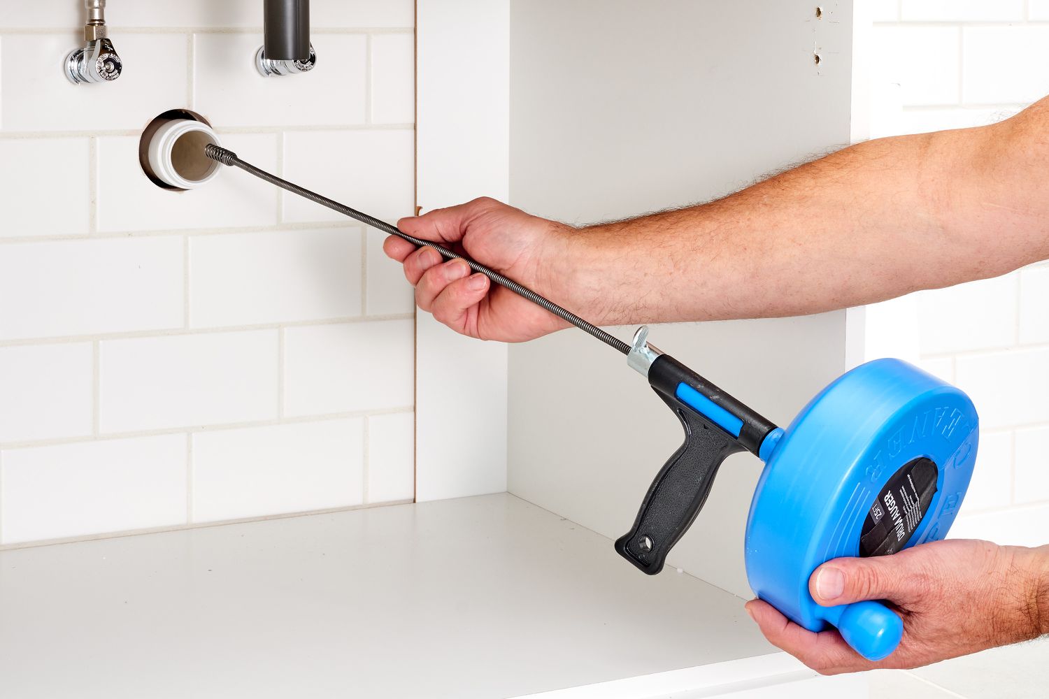 Handheld auger cable pushed into sink drain