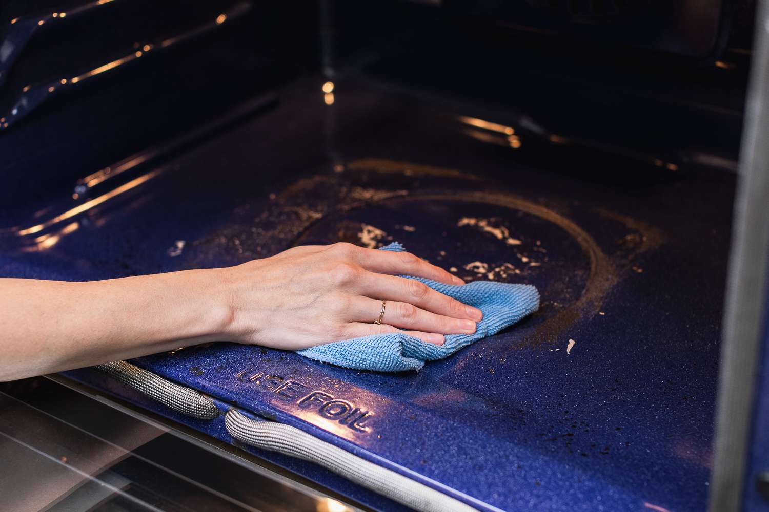 Paño de microfibra húmedo limpiando los residuos de la parte inferior del horno