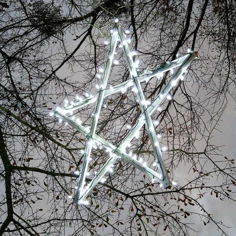 Ein hölzerner beleuchteter Stern, der an einem Baum hängt