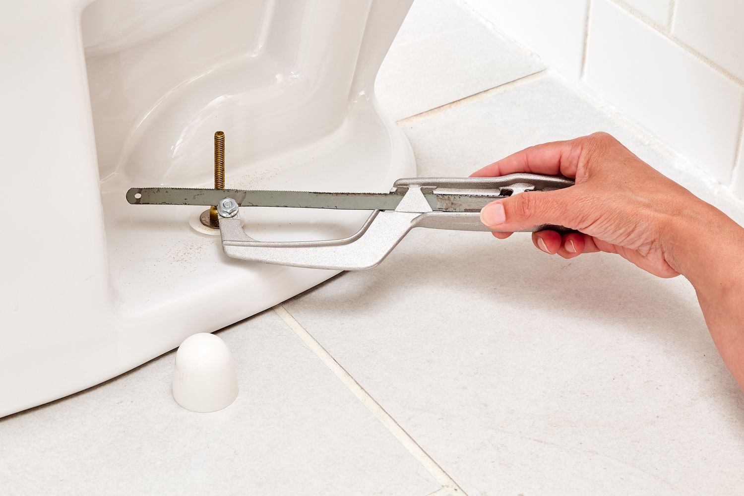 Kleine Bügelsäge schneidet Metallbolzen am Toilettenboden ab