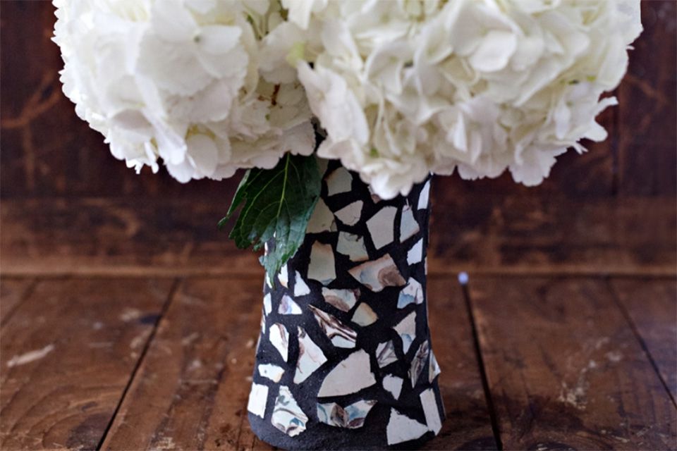 Un jarrón de mosaico negro con con flores