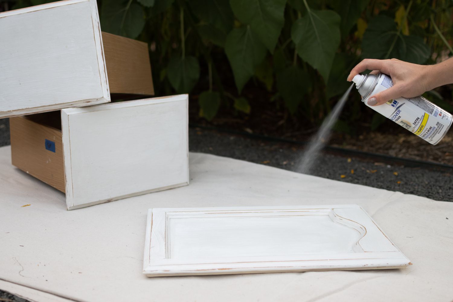 Primer sprayed on bathroom cabinet doors outside on white sheet