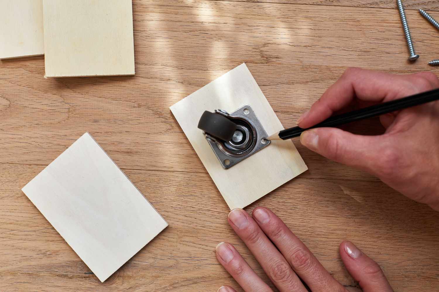 Wheel screw holes marked with pencil on square plywood piece