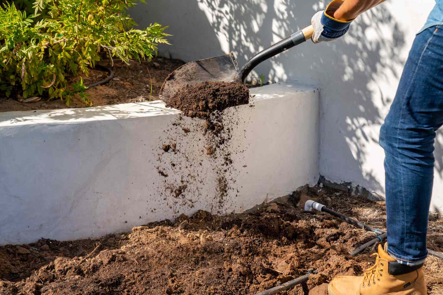 Bodenverbesserungsmittel mit Schaufel auf dem Gartenbeet verteilen