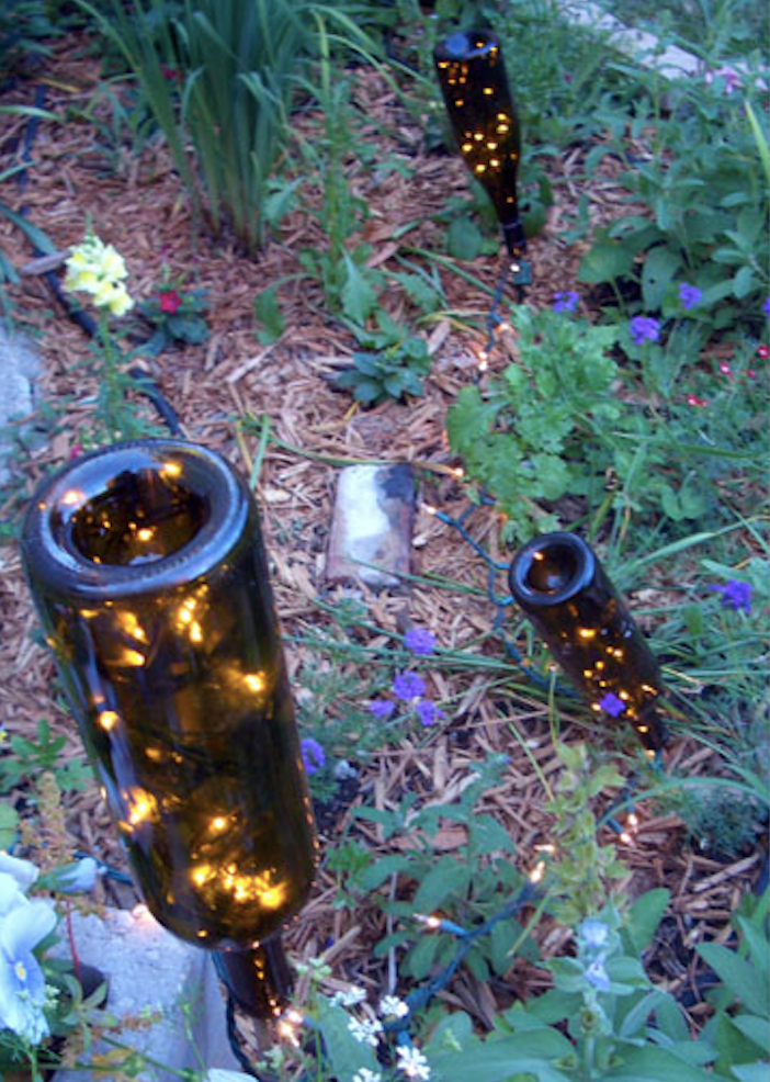 Flaschen mit glitzernden Lichtern, die als Gartenlichter im Gras verwendet werden