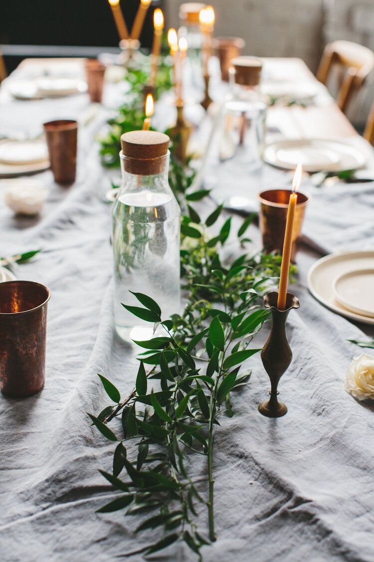 Mesa posta com vegetação, detalhes em cobre e velas de cera de abelha