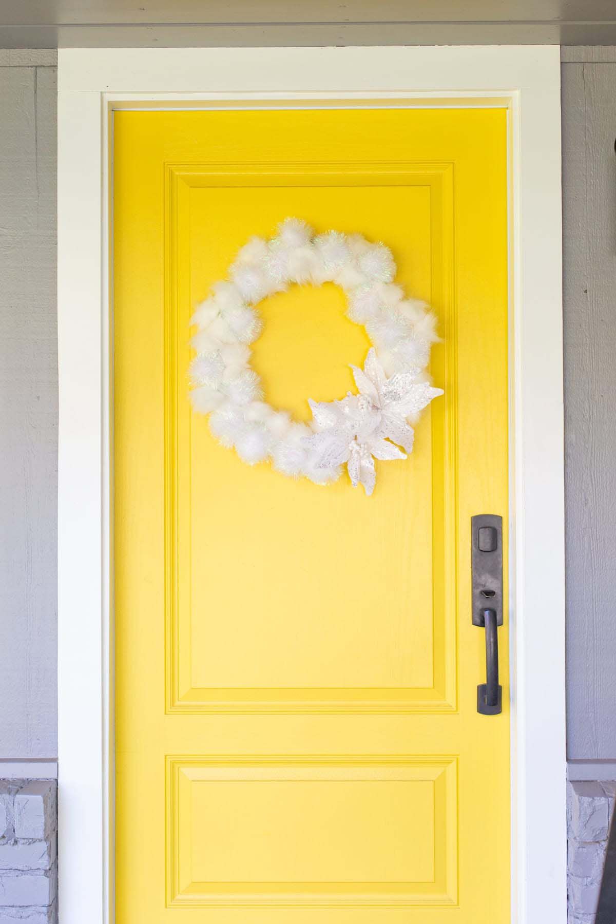 Eine leuchtend gelbe Tür mit einem weißen flauschigen Kranz