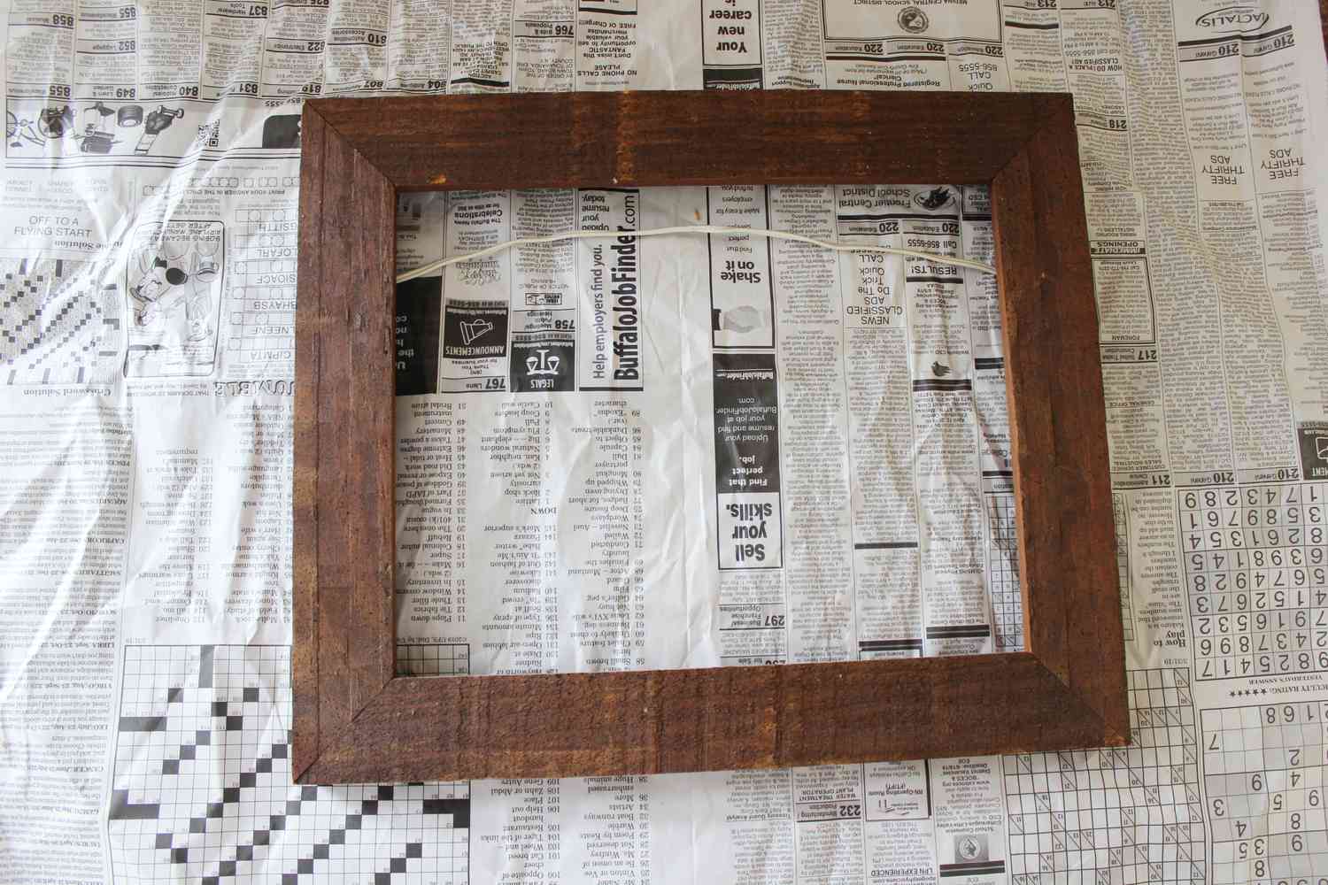 leerer Holzbilderrahmen auf Zeitung