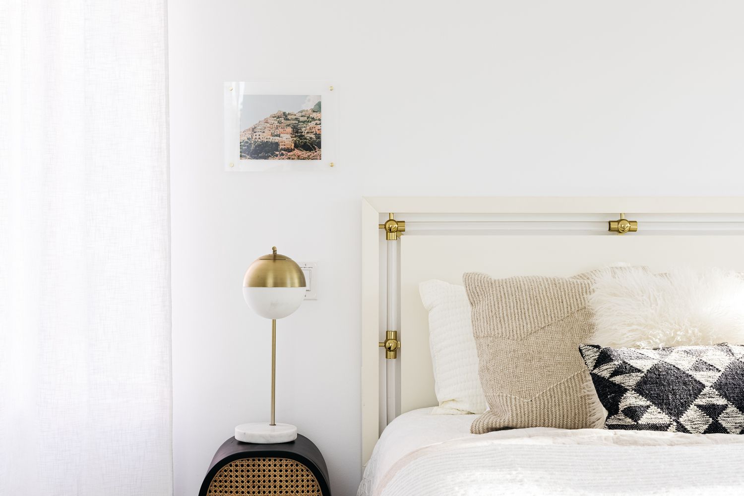 Dormitorio luminoso con cortinas blancas junto a la lámpara de cabecera y cama de color neutro