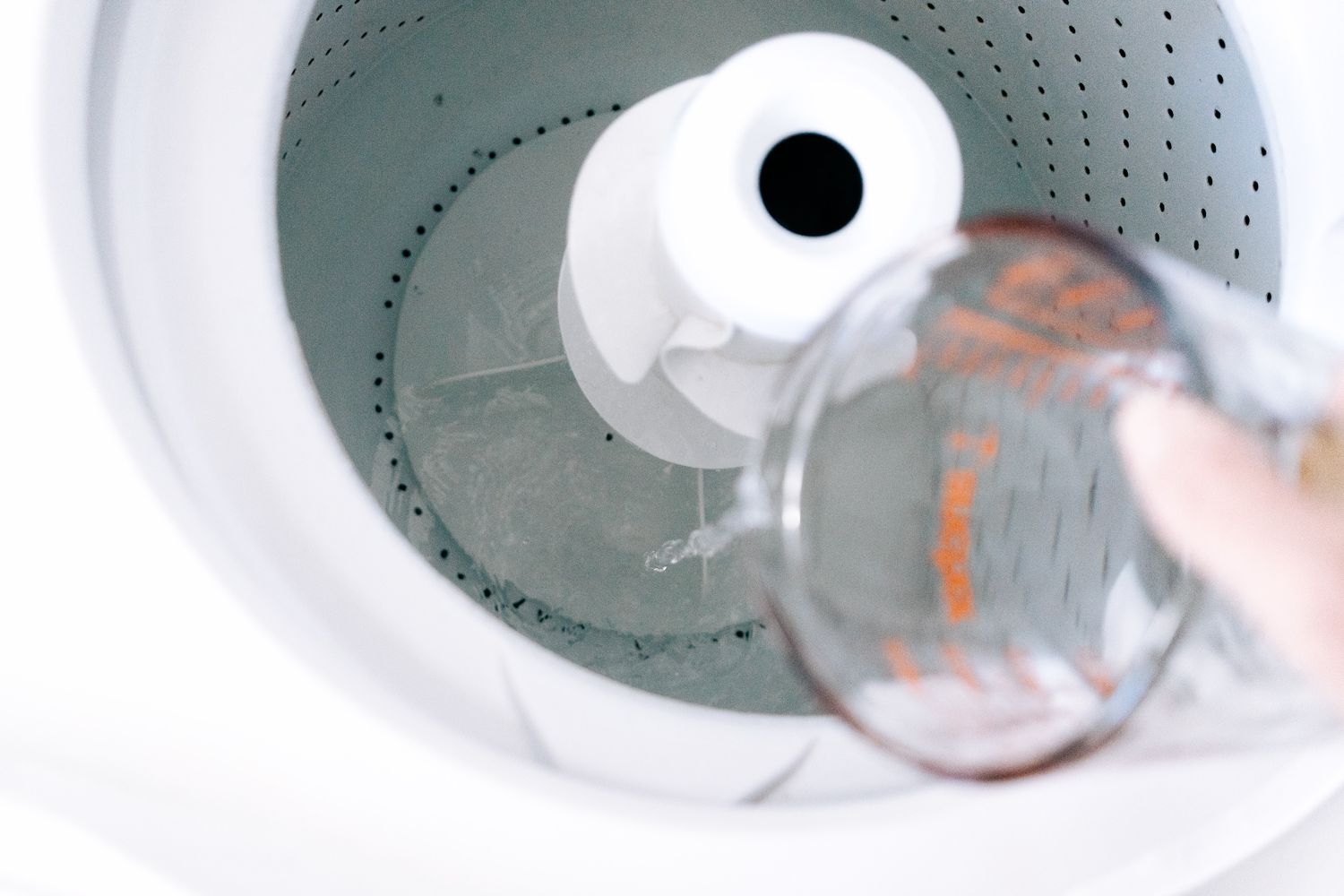 adding distilled white vinegar to the washer drum