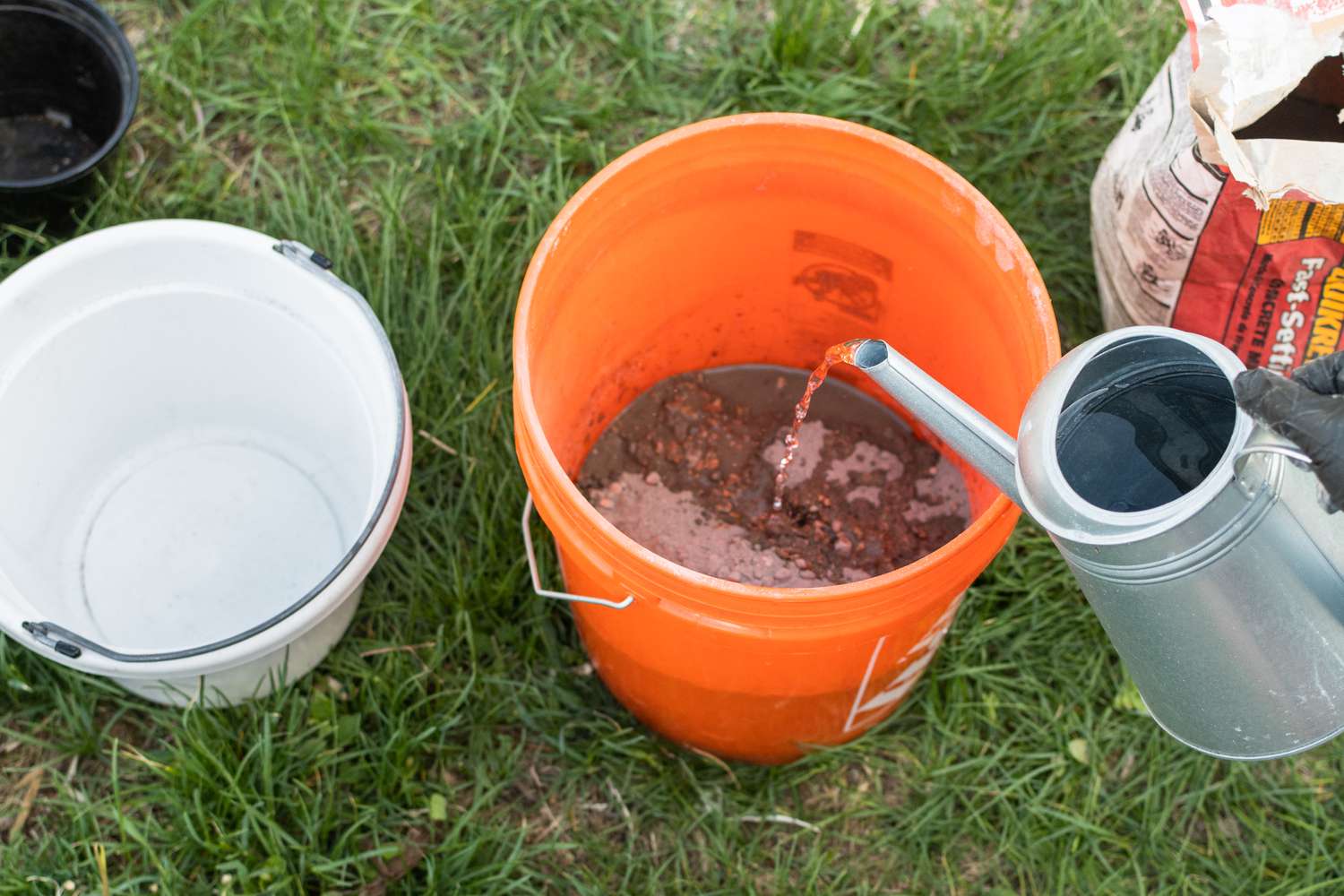 Zementmischung und Wasser in einem großen orangefarbenen Eimer zum Mischen